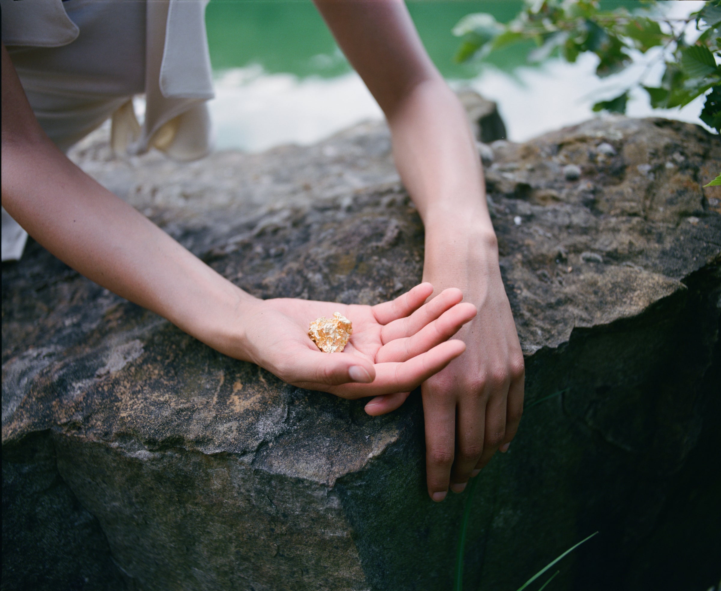 Une pépite d'or tenue à la main par une personne au bord d'une rivière en Guyane française